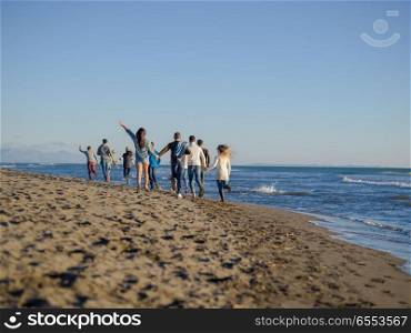 group of young friends spending day together running on the beach during autumn day. Group of friends running on beach during autumn day