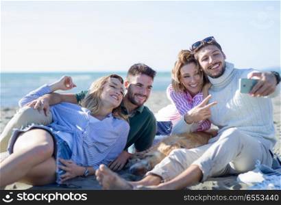 Group Of Young Friends Spending The Day On A Beach during autumn day. Group of friends having fun on beach during autumn day