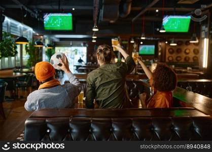 Group of young friends watching football on tv screen at sports bar. Young people soccer fans shouting, laughing and smiling sitting at table with raised beer glasses view from back. Group of young friends watching football on tv screen at sports bar