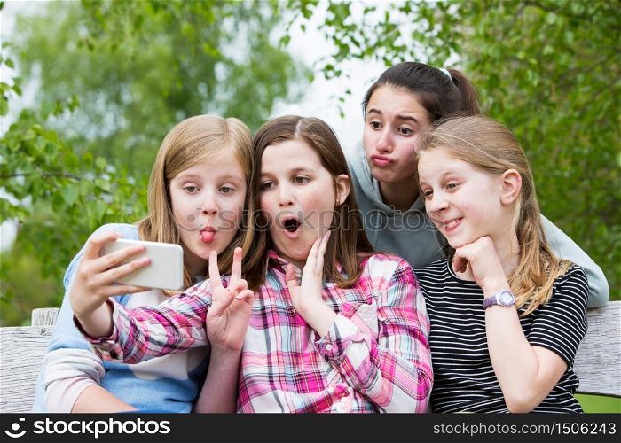 Group Of Young Girls Posing For Selfie In Park