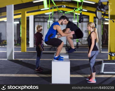 group of young healthy athletic people training jumping on fit box at crossfitness gym. athletes working out jumping on fit box