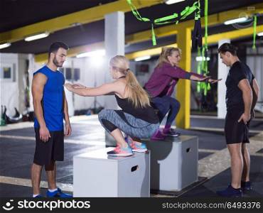 group of young healthy athletic people training jumping on fit box at crossfitness gym. athletes working out jumping on fit box
