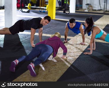 group of young healthy people doing pushups at crossfitness gym. young healthy people doing pushups