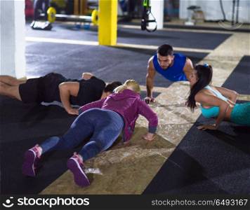 group of young healthy people doing pushups at crossfitness gym. young healthy people doing pushups