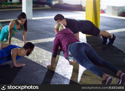 group of young healthy people doing pushups at crossfitness gym. young healthy people doing pushups