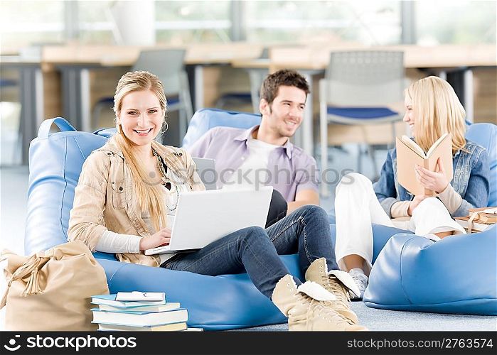 Group of young high-school students relaxing with books and laptop