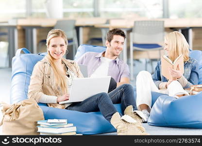 Group of young high-school students relaxing with books and laptop