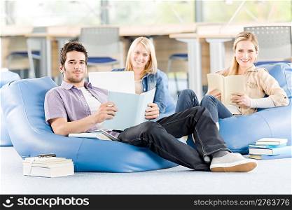 Group of young high-school students relaxing with books and laptop