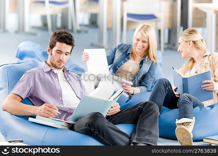 Group of young high-school students relaxing with books and laptop