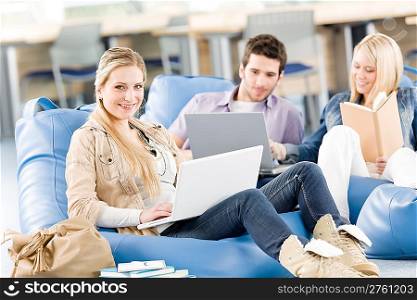 Group of young high-school students relaxing with laptop and book