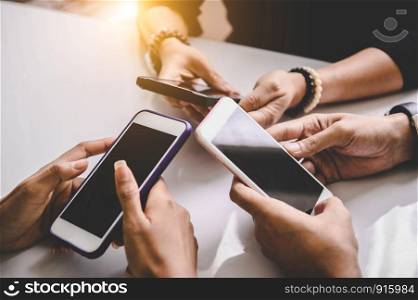 Group of young hipsters holding phone in hands at office. Friends having fun together with smartphones. Technology and communication concept. Black screen. Side view of teenager team using phones