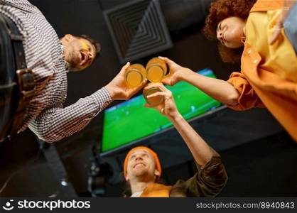 Group of young male and female friends celebrating win of favorite football soccer team clinking beer glasses while resting in sports bar. View from bottom, selective focus. Group of friends celebrating win clinking beer glasses in sports bar