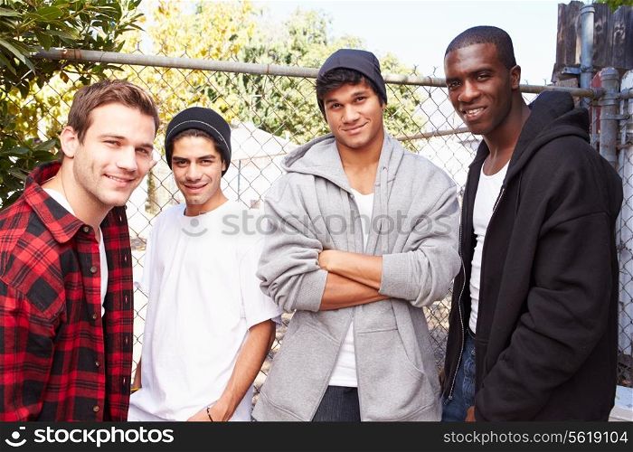 Group Of Young Men In Urban Setting Standing By Fence