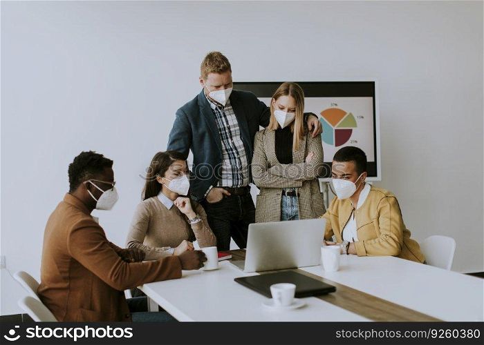 Group of young multiethnic business people working together with facial protection masks and preparing new project on a meeting in the office
