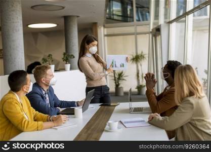 Group of young multiethnic business people working together with facial protective masks and preparing new project on a meeting in office