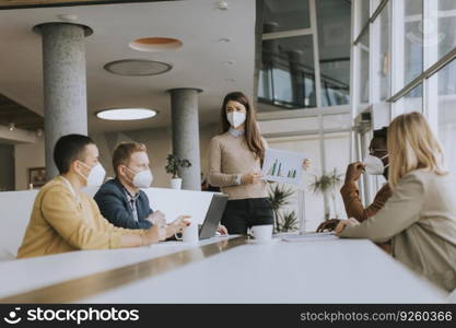 Group of young multiethnic business people working together with facial protective masks and preparing new project on a meeting in office