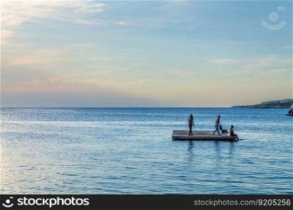 Group of young people are enjoying themselves on a floating dock in the Caribbean Sea