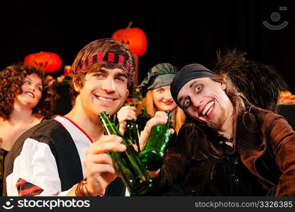 Group of young people celebrating a carnival or Halloween party in costumes drinking beer