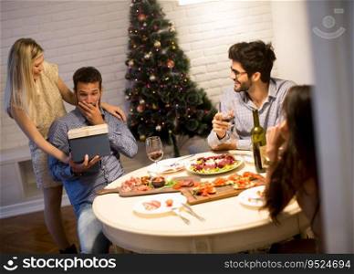 Group of young people celebrating Christmas and opening presents in the room