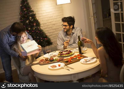 Group of young people celebrating Christmas and opening presents in the room