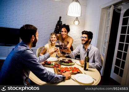 Group of young people celebrating New Year and drinking red wine