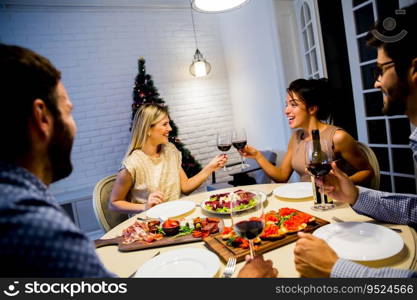 Group of young people celebrating New Year and drinking red wine