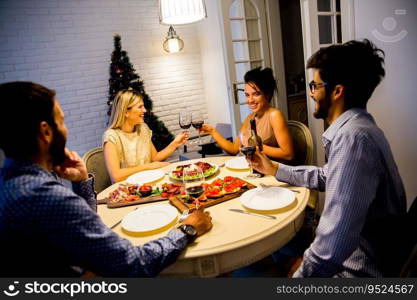 Group of young people celebrating New Year and drinking red wine