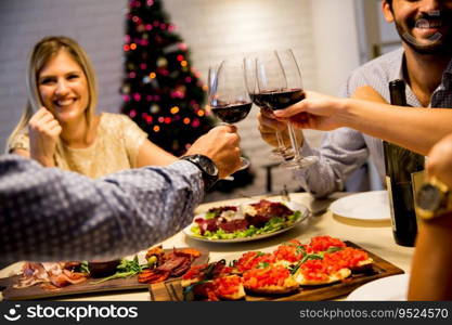 Group of young people celebrating New Year and drinking red wine