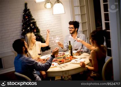 Group of young people celebrating New Year and drinking red wine