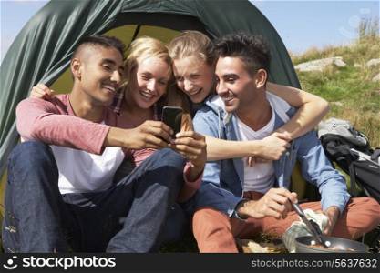 Group Of Young People Checking Mobile Phone On Camping Trip