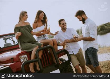 Group of young people drinking and having fun by car outdoor at hot summer day