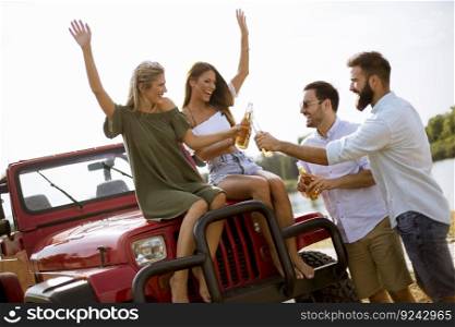 Group of young people drinking and having fun by car outdoor at hot summer day