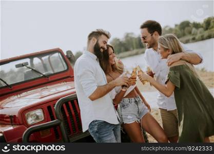 Group of young people drinking and having fun by car outdoor on a sunny hot summer day
