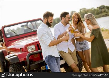Group of young people drinking and having fun by car outdoor on a sunny hot summer day