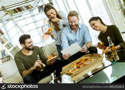 Group of young people eating pizza, drinking cider and watching digital tablet in the room
