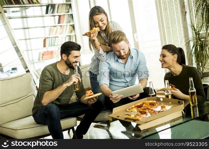 Group of young people eating pizza, drinking cider and watching tablet in the room