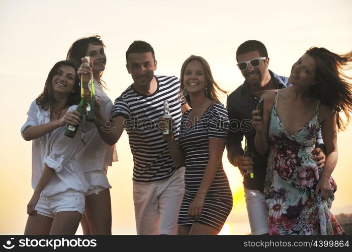 Group of young people enjoy summer party at the beach on beautiful sunset