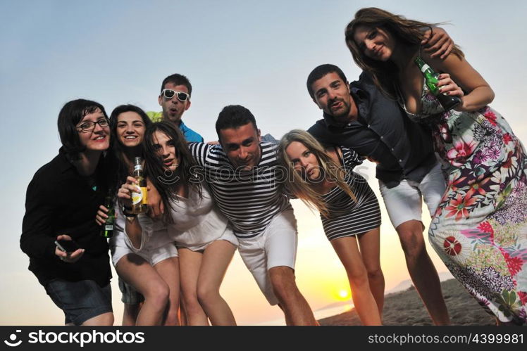 Group of young people enjoy summer party at the beach on beautiful sunset