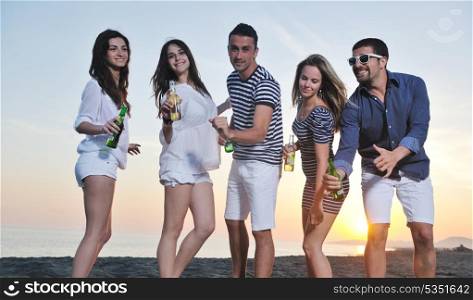 Group of young people enjoy summer party at the beach on beautiful sunset
