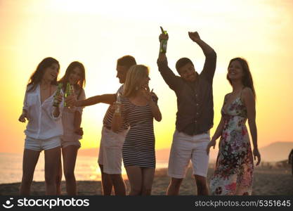 Group of young people enjoy summer party at the beach on beautiful sunset