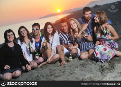 Group of young people enjoy summer party at the beach on beautiful sunset