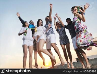 Group of young people enjoy summer party at the beach on beautiful sunset