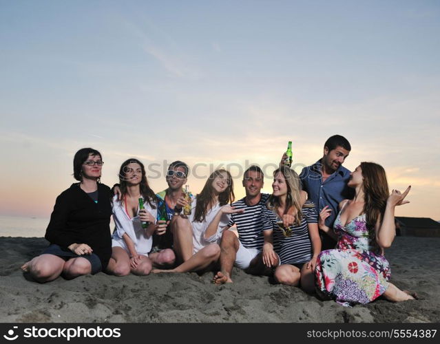 Group of young people enjoy summer party at the beach on beautiful sunset