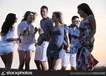 Group of young people enjoy summer party at the beach on beautiful sunset