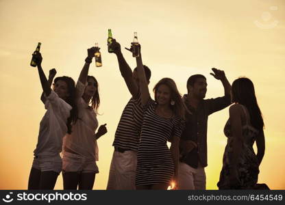 Group of young people enjoy summer party at the beach on beautiful sunset