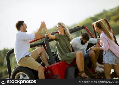 Group of young people  having fun by car outdoor on a sunny hot summer day