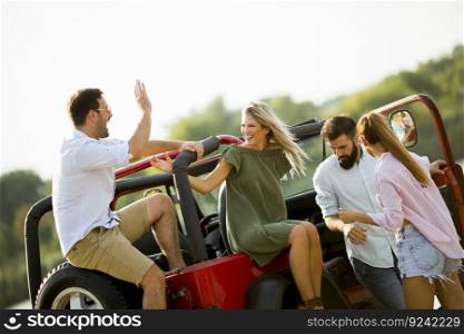 Group of young people  having fun by car outdoor on a sunny hot summer day