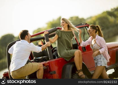 Group of young people  having fun by car outdoor on a sunny hot summer day