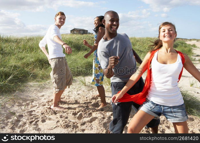 Group Of Young People Having Fun Dancing On Beach Together
