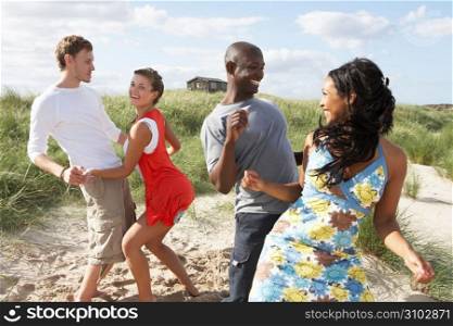 Group Of Young People Having Fun Dancing On Beach Together